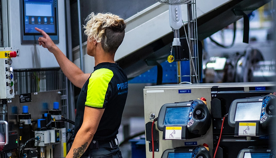 Person wearing a T-shirt with “Pipelife” on the back, operating a machine in production (photo)