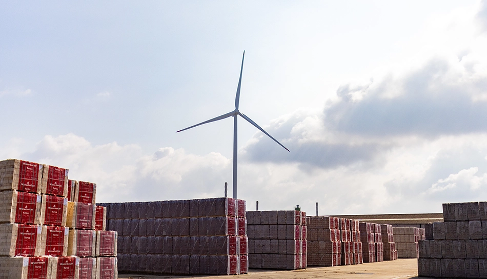 Low-angle view of a wind turbine and stacks of bricks at the wienerberger brick factory (photo)
